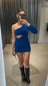 Vestido corto azul brillante de lurex, con un hombro descubierto, manga larga y abertura en la cintura.