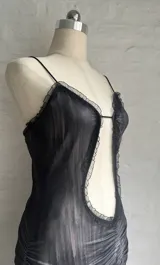 Minivestido gris con estampado difuminado, escote halter con detalle de encaje negro, abertura en el abdomen y falda con volados.