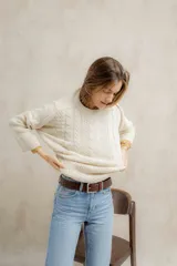 Sweater tejido en hilo de algodón color crudo, con cuello redondo, corte holgado, hombros caídos y diseño de ochos en la parte delantera.