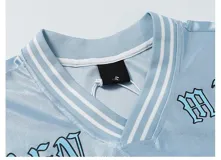 Remera estilo jersey de fútbol o americana, color celeste claro, con paneles de tela satinada y malla microperforada. Presenta cuello en V con ribete blanco, el número "90" grande en el frente con borde negro, y texto en la parte superior que dice "BAEN MADE" y "Madcapsclub".