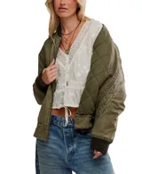 Blusa blanca de manga larga, confeccionada en algodón con bordados florales y detalles de encaje en el escote y mangas. Presenta un escote en V con botones frontales y un cordón ajustable en el bajo para fruncir.