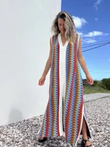 Vestido largo de tejido con diseño geométrico en tonos celeste, marrón, rojo y blanco. Tiene escote en V y aberturas laterales.