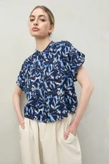 Camisa de manga corta con estampado abstracto en tonos azul, celeste y blanco. Tiene cuello mao, silueta relajada y cierre frontal con botones.