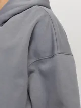 Hoodie gris de manga larga con capucha, corte holgado y bolsillo canguro.