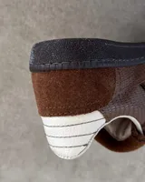 Sneakers bajas de cuero vacuno color bordó con suela marrón.