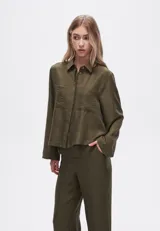 Camisa verde militar de poliéster con cuello clásico, cierre frontal con botones, dos bolsillos con fuelle en el pecho y mangas largas con puños abotonados.