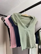 Remera corta color verde agua, con escote en V y detalle de puntilla blanca en el borde.