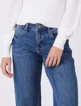 Jean de mezclilla azul, modelo wide leg con tiro medio/alto, cierre frontal y bolsillos. Presenta costura lateral asimétrica y bajo deshilachado.