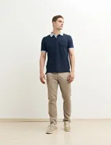 Remera polo blanca de piqué con cuello y puños en azul marino. Tiene tapeta de dos botones y bolsillo de parche en el pecho.