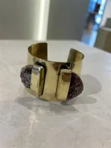 Brazalete rígido dorado con dos amatistas irregulares en los extremos.