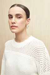 Sweater de punto color salmón con cuello redondo y mangas anchas. Presenta un diseño calado en la parte superior y tejido tramado horizontal en el resto del cuerpo.