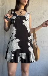 Vestido corto negro con estampado floral blanco, de corte suelto y sin mangas.