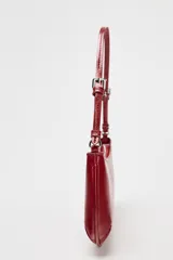Bolso de hombro color rojo con efecto craquelado, asa corta y cierre de cremallera.