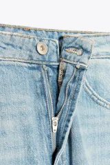 Pantalón de jean azul oscuro, tiro medio, corte amplio tipo baggy balloon con costuras torcidas y cinco bolsillos. Cierre frontal con cremallera y botón metálico.