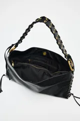 Bolso de hombro alargado color negro, con detalle de pasados metálicos en los laterales y asa trenzada. Tiene doble bolsillo interior con cremallera y cierre mediante botón imantado.