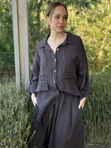 Camisa oversize rosada de lino, con cuello clásico, cierre frontal con botones, dos bolsillos de parche en el pecho y mangas largas con puños abotonados.