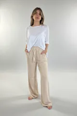 Pantalón de jersey color beige, de corte amplio, con bolsillos laterales y cintura elastizada con cordón ajustable.