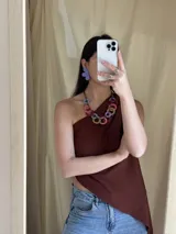 Collar con aros de acrílico entrelazados con tiento sintético color chocolate. Tiene nudo ajustable para regular el largo.