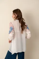 Túnica azul con bordados florales, cuello camisero y botones forrados.