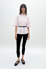Camisa rosada de corte holgado, con cuello solapa, cierre frontal con botones y mangas cortas.