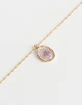 Cadena corta dorada con dije circular transparente que contiene una flor amarilla.