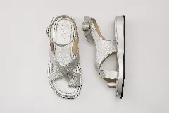 Sandalia de cuero color plateado con plataforma. Presenta tiras cruzadas en la parte delantera, una tira con agarre para el dedo gordo y una pulsera ajustable con hebilla en el tobillo.