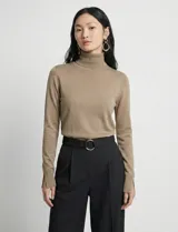 Polera de punto fino marca Nienty, color tostado, con cuello alto, manga larga y detalle de tajo en los puños.