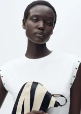 Camiseta negra de tejido de canalé con cuello redondo y sisas con ojales metálicos.