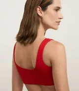 Top deportivo de microfibra color rojo, sin copa, con breteles rectos, escote en V y detalle de torcido en el busto.