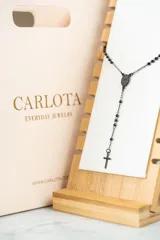 Collar tipo rosario negro con cuentas y cruz colgante en acero quirúrgico.