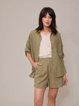 Camisa verde militar de algodón y lino, con corte clásico, cuello camisero, mangas largas con puños abotonados y cierre frontal con botones.