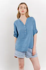 Camisa azul de lino con escote en V abotonado, bolsillo frontal y mangas 3/4 con trabilla.