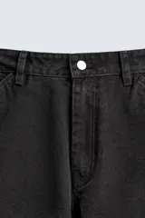 Pantalón negro de corte amplio, confeccionado en tejido de algodón con efecto lavado. Presenta bolsillos frontales, traseros de parche, tira multifunción y bolsillos laterales en las perneras. Cuenta con cierre frontal con cremallera y botón.