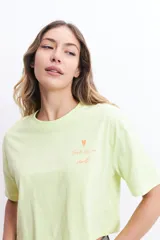 Remera corta color verde lima con estampado frontal de un corazón y la frase "love is a verb".