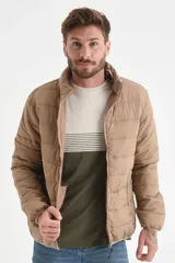 Campera acolchada color beige, con cuello alto y cierre frontal. Presenta costuras horizontales que crean el efecto capitoné.