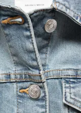 Chaqueta de jean celeste de corte clásico, con cuello camisero, cierre frontal con botones metálicos, bolsillos delanteros con solapa y puños abotonados.