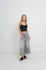 Pantalón jean gris de tiro alto, corte ancho y largo 3/4 con detalle de flecos en el ruedo.