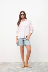 Camisa de manga larga color rosa pastel, con cuello clásico y cierre frontal con botones.