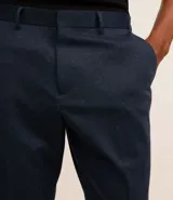 Pantalón de vestir azul marino, de corte recto, con bolsillos laterales y traseros. Se ajusta a la cintura con cinturón de cuero marrón.