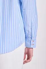 Camisa celeste a rayas verticales blancas, de manga larga con puños elásticos y volados en el frente.