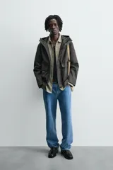 Parka relaxed fit color negro confeccionada en tejido de lino que repele el agua. Tiene cuello con capucha ajustable, mangas largas con puños abotonados, bolsillos frontales con solapa y cierre frontal con cremallera oculta por solapa con botones a presión.