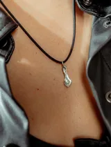 Collar con dije irregular de plata y cordón fino negro.