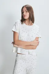 Conjunto de pijama blanco con estampado de lunares negros, compuesto por una remera de manga corta y un pantalón largo.