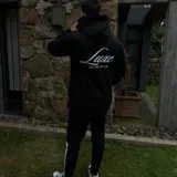 Buzo hoodie negro de corte oversize, con capucha, bolsillo frontal y estampa blanca en la espalda con la leyenda "Luxe" y "The Luxe Vip Club".