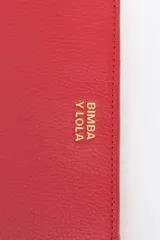 Billetera mediana de piel vacuna color rojo, con cierre de cremallera y tirador de tejido con el logo de la marca. Presenta tarjetero y monedero interior con logo grabado.