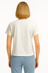 Remera celeste de manga corta y cuello redondo, con estampado de sardinas sobre fondo a cuadros rojos y blancos. Incluye texto con los nombres de las ciudades de Cagliari y Sardina.