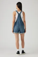 Jardinero corto de jean azul con tirantes ajustables, bolsillo en el pecho y botones metálicos a los lados.