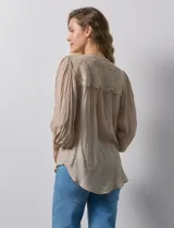 Blusa color beige de gasa, marca Figueroa & Flower. Cuello a la base, escote en V y abertura central con botones. Hombros y espalda en crochet. Manga 3/4 amplia con puño y botón.