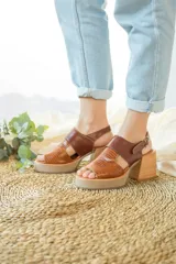 Sandalias de cuero color marrón con plataforma de madera, punta descubierta y tira trasera con hebilla.