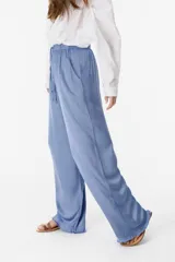 Pantalón tipo pijamero satinado de color azul, con pretina ajustable y detalle de flaco en el bajo.